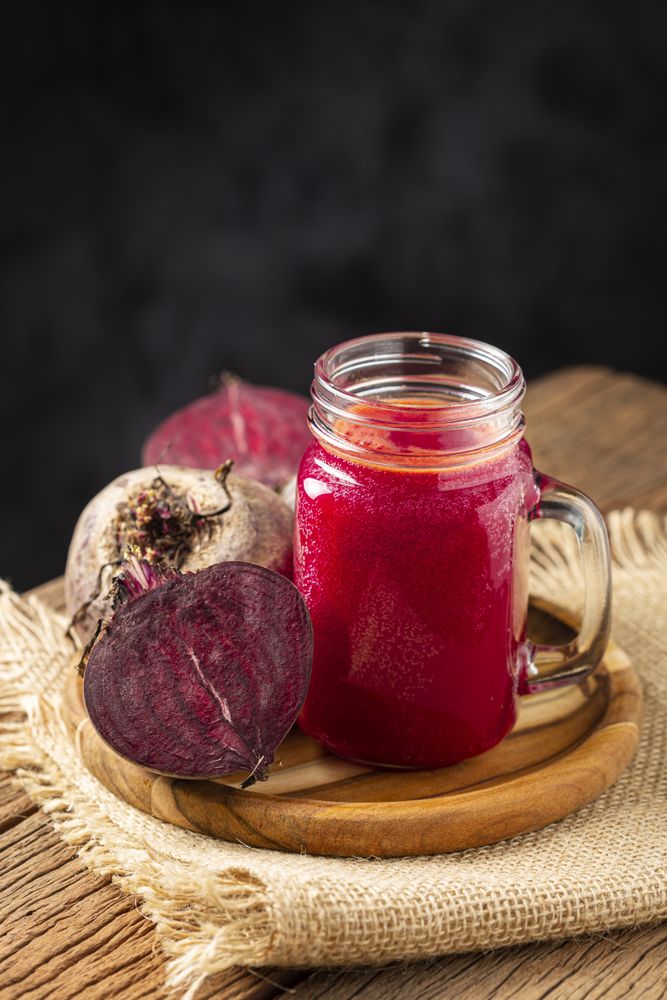 Red beet juice in a glass cup on the wooden table.