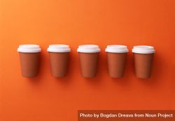 Single row of disposable coffee cups on orange background 4dEYab