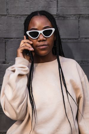Black woman talking on smartphone near brick wall