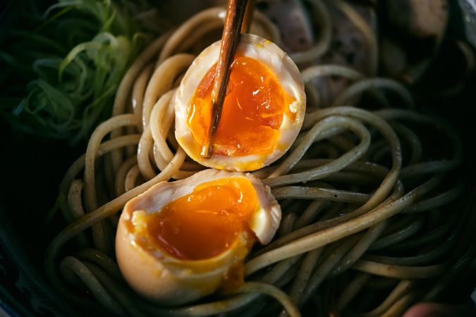 Halves of soft boiled egg on noodles