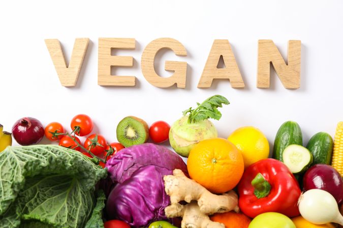 Word Vegan, different vegetables and fruits isolated on blank background