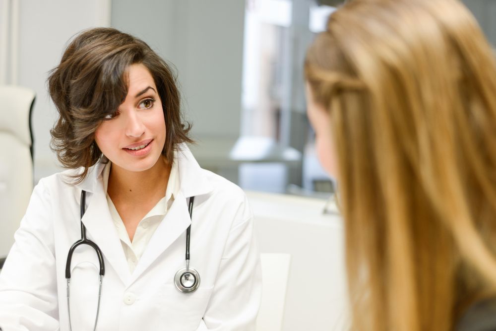 Serious female doctor with female patient in clinic