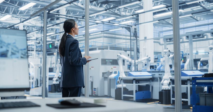 Electronics Manufacturing Technician Working on Tablet Computer at a Factory Space. Asian Female Specialist Developing, Maintaining, and Fine-Tuning Programs for Machine Production and Assembly