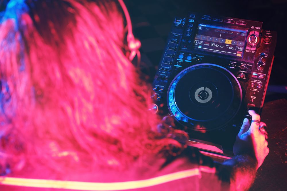 Faceless DJ in headphones playing song in club