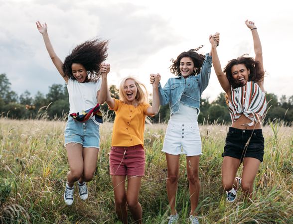 Group of diverse women jumping together outdoors