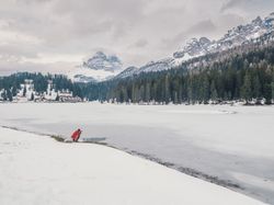 Unrecognizable person standing in snow surrounded by forest and mountains