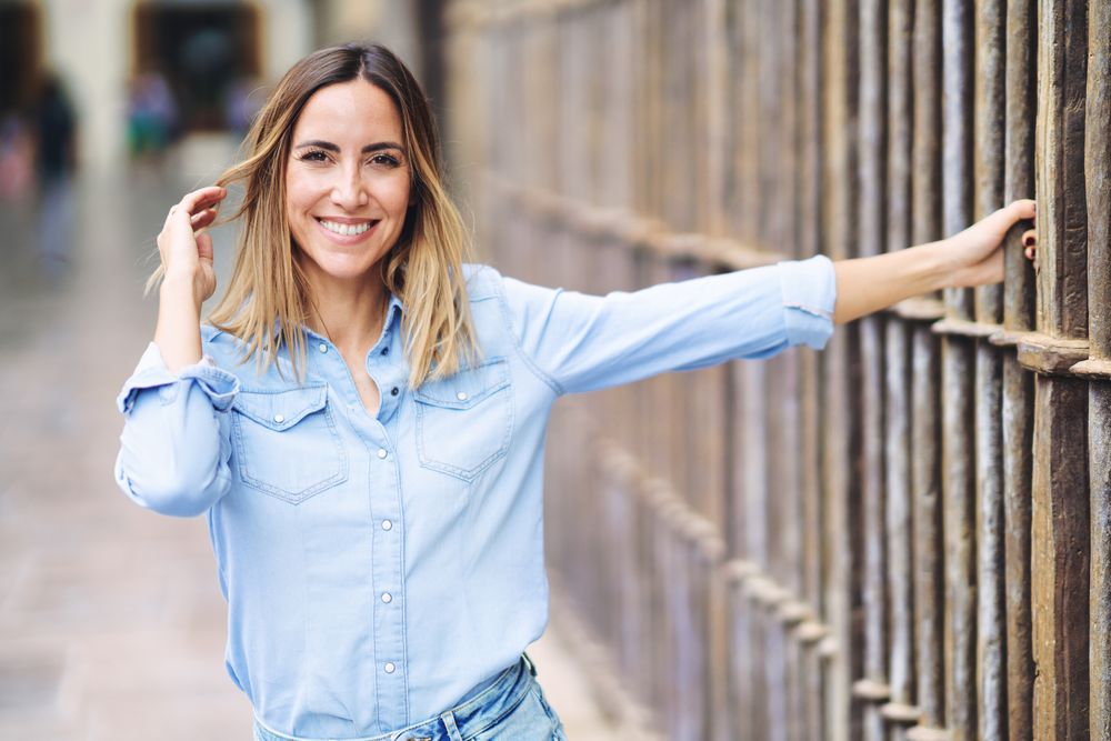 Woman wearing denim holding fence outside