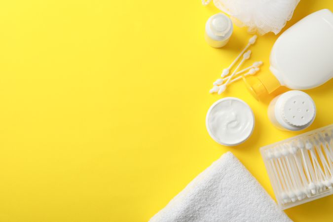 Baby hygiene accessories on yellow background, top view and space for text