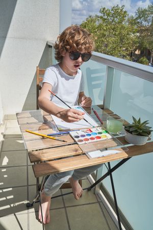 Kid painting with watercolor on balcony