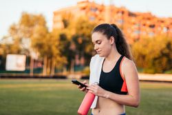 An athletic woman resting with her smartphone after running.