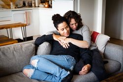 Loving female couple tenderly holding each other in living room