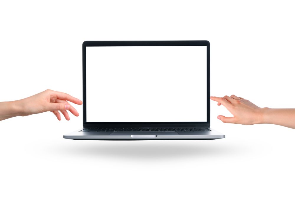 Two hands are reaching out towards a blank laptop screen
