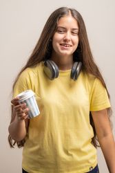 A young female student holding a paper cup of coffee, on a break.