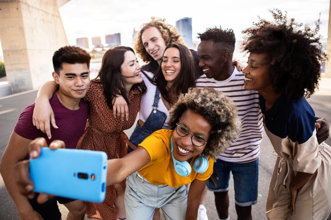 Group of smiling people taking selfie together outdoors