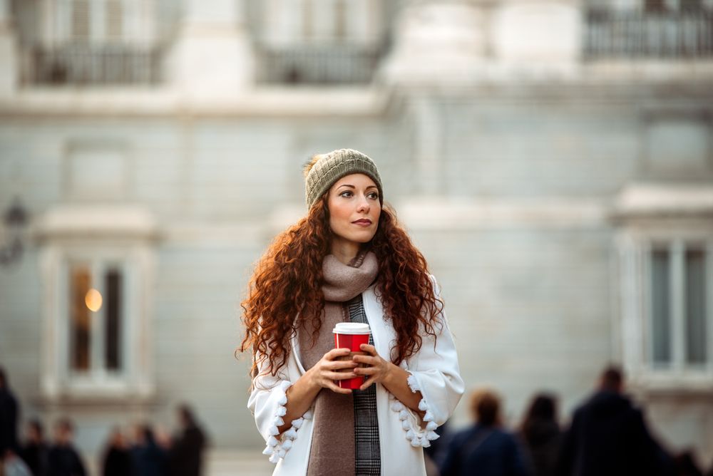 Woman drinking coffee wandering in the streets of Madrid on winter