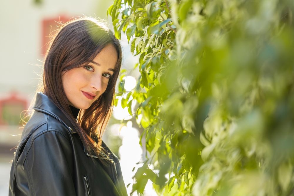 Charming woman beside bush leaves on street
