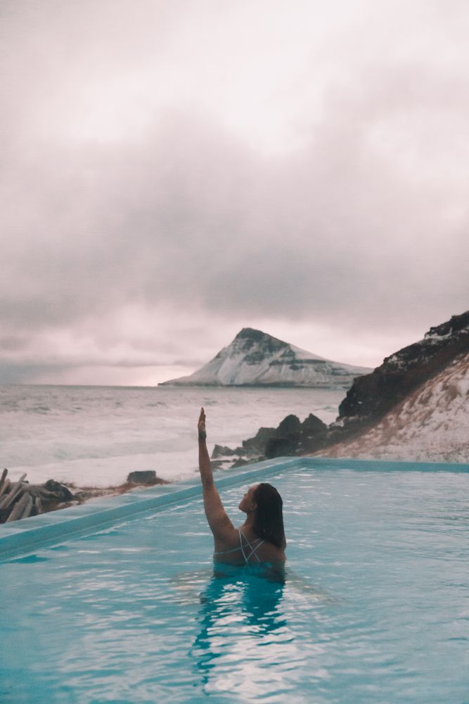 Woman in pool near sea and hills on shore