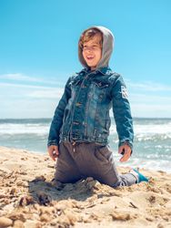 Happy boy sitting on sand near sea