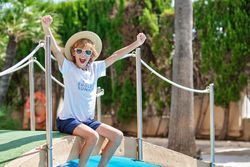 Cheerful boy sitting on footbridge over swimming pool at resort