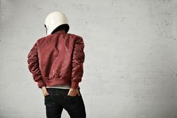 Rearshot of man in dark red leather jacket wearing helmet with hands in back pocket