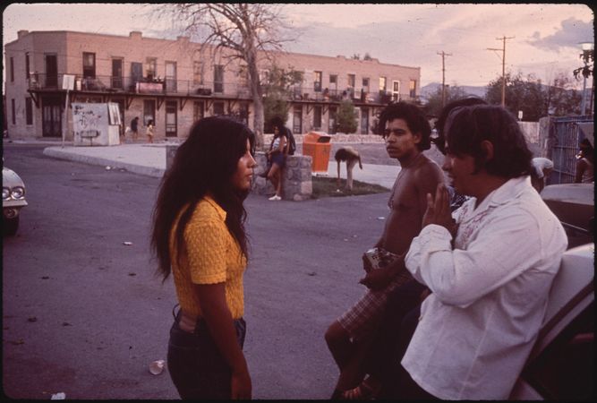 Latina woman talking to group of men in El Paso in the 1970s