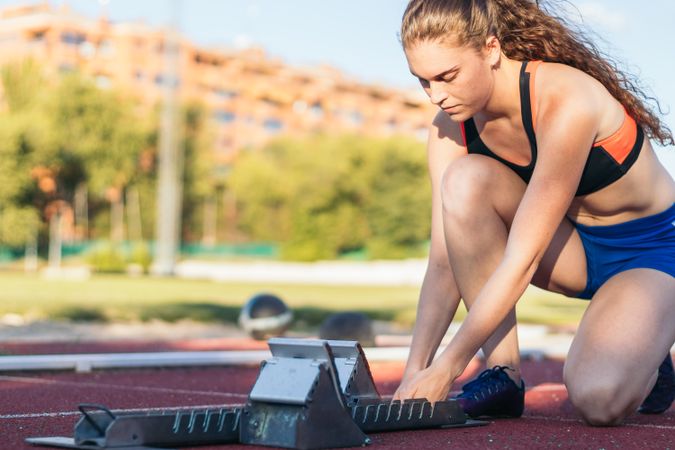 A female athlete getting ready to run on an athletics track.