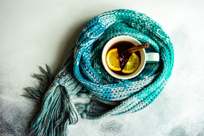 Tea time concept with teal scarf wrapping around cup of tea
