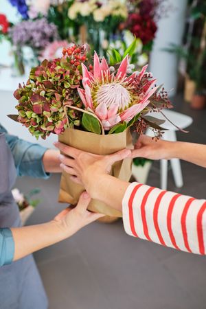 Unrecognizable female florist giving bouquet of flowers to custo