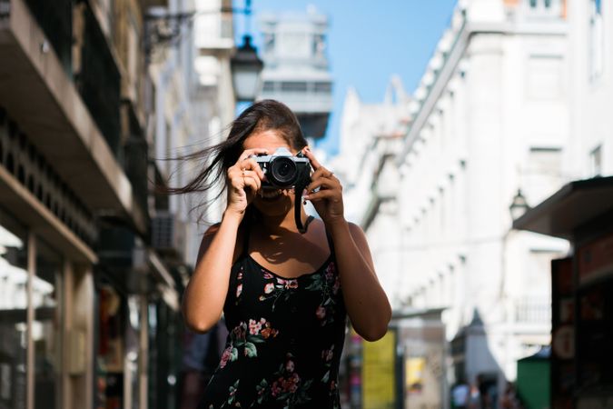 Casual woman taking photo with camera while standing on street