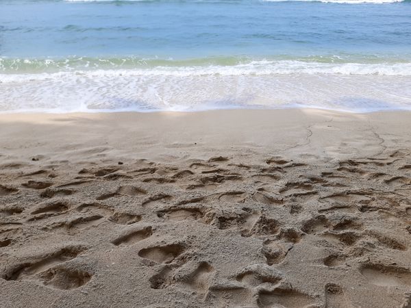 Footprints on sandy beach near ocean waves in Angso Duo Island, Pariaman, Indonesia