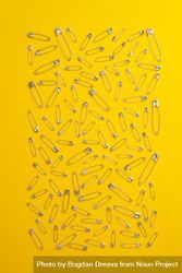 Scattered safety pins on yellow background 0LYqg5