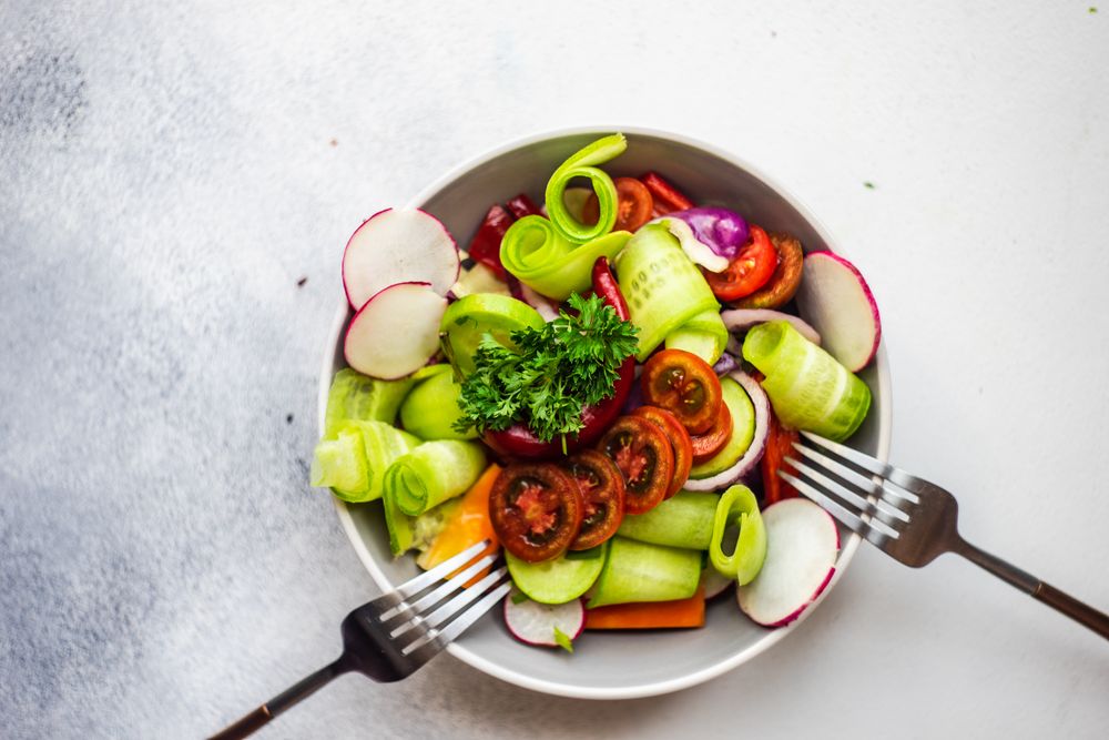 Healthy raw salad with freshly chopped vegetables served with two forks with copy space