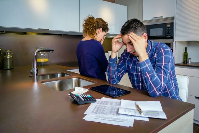 Couple arguing as they go through their bills together in the kitchen