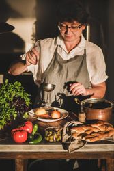 Woman with short hair and glasses with ladle of stew