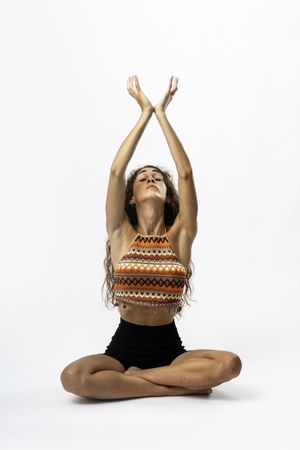 Spiritual woman with natural hair meditating with arms up in boho style