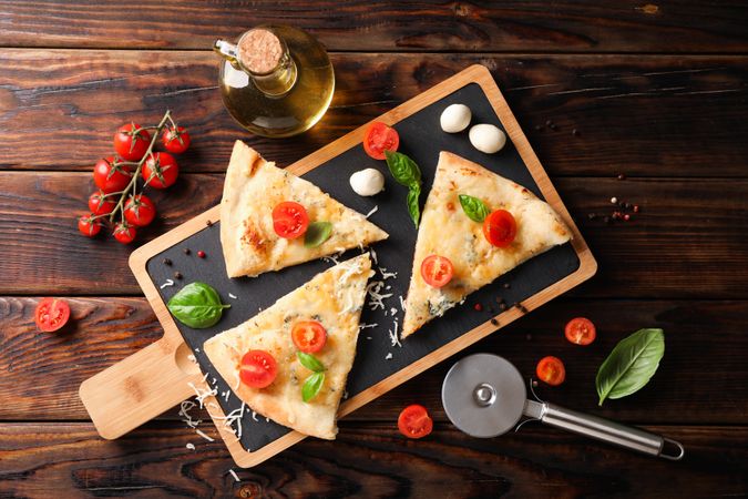 Pieces of pizza and ingredients on wooden background, top view
