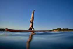 Unrecognizable woman practicing Supported Headstand on SUP board