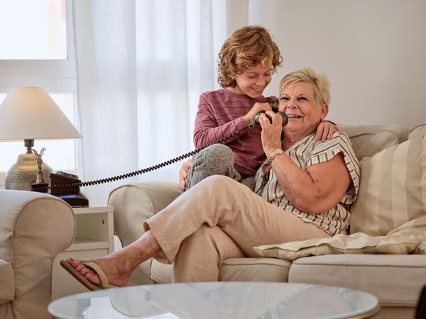 Boy with grandmother talking on telephone