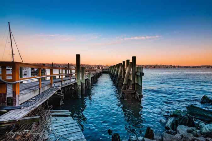 Brown wooden dock on sea during sunset