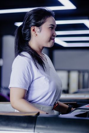 Focused woman exercising on treadmill in modern lighted gym