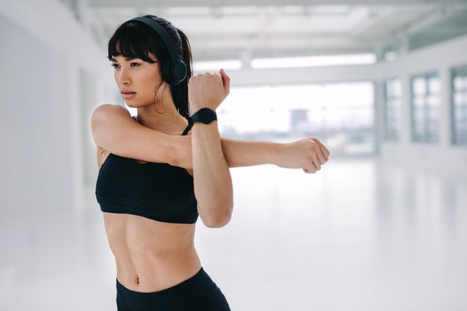 Young woman stretching her arms at gym as warmup workout at fitness studio