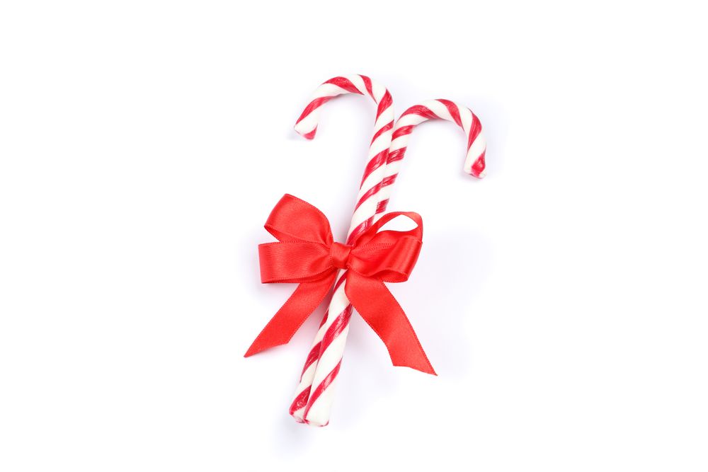 Sweet candy canes with bow isolated on plain background