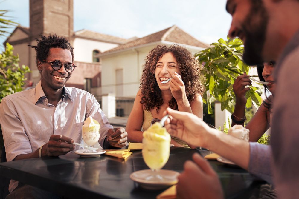 Group of friends laughing at an outdoor cafe in Italy