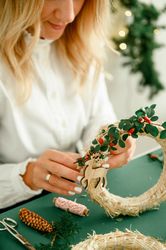 A woman is crafting a wreath for Christmas. Natural natural decoration, DIY, traditional Christmas celebration.