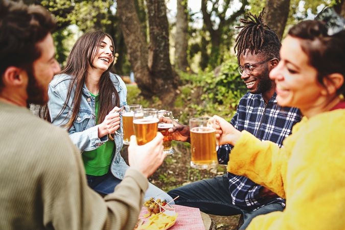 Multi-ethnic group of friends gather outside to chat and have a beer together