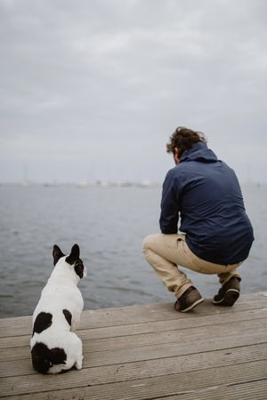 Man and dog sitting on pier