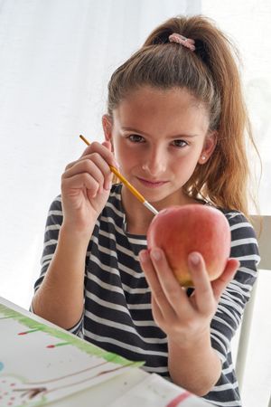 Girl painting on apple at table