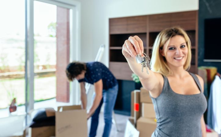 Woman showing keys while her husband unpacks