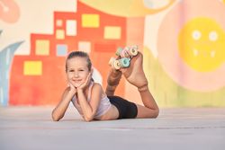 Cheerful young girl lying on ground near graffiti wall