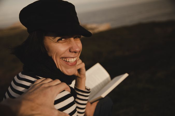 Hand on shoulder of smiling woman with book